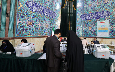 Des Iraniens votant dans un bureau de vote à Téhéran lors du second tour des élections législatives, le 10 mai 2024. (Crédit : Atta Kenare/AFP)