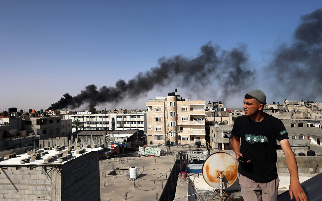 Un homme regarde une épaisse fumée noire s'élever de l'incendie d'un bâtiment à Rafah, dans le sud de la bande de Gaza, le 10 mai 2024. (Crédit : AFP)
