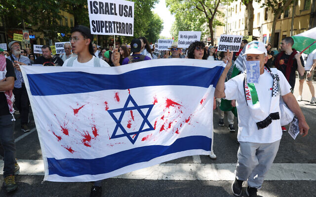 Des manifestants brandissant un drapeau israélien taché de peinture rouge lors d'une manifestation de soutien au peuple palestinien de la bande de Gaza, à Madrid, le 11 mai 2024. (Crédit : Pierre-Philippe Marcou/AFP) Des manifestants brandissant un drapeau israélien taché de peinture rouge lors d'une manifestation de soutien au peuple palestinien de la bande de Gaza, à Madrid, le 11 mai 2024. (Crédit : Pierre-Philippe Marcou/AFP)