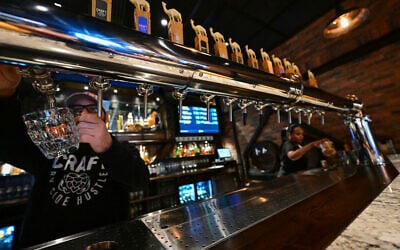 Des barmans servent de la bière à la pression dans une brasserie artisanale à Abu Dhabi, le 7 mai 2024. (Crédit ! Giuseppe CACACE / AFP)