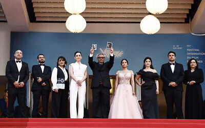 Le réalisateur iranien Mohammad Rasoulof (C) tient le portrait de l'acteur iranien Missagh Zareh (G) et de l'actrice iranienne Soheila Golestani (D) lors de la 77e édition du Festival de Cannes à Cannes, dans le sud de la France, le 24 mai 2024. (Crédit : Sameer Al-Doumy / AFP)