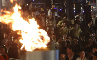 Des hommes juifs ultra-orthodoxes regardent un feu brûler tout en célébrant la fête juive de Lag BaOmer dans le quartier de Sheikh Jarrah de Jérusalem-Est, le 25 mai 2024. (Ahmad Gharabli/AFP)