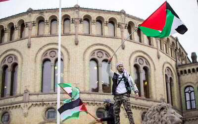 Un homme agitant le drapeau palestinien devant le bâtiment du Parlement norvégien lors d'une manifestation à Oslo, le 28 octobre 2023. (Crédit : Frederik Ringnes/NTB via AP)