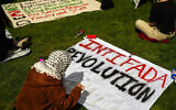 Une personne préparant une pancarte portant l'inscription "Intifada Revolution" lors d'un campement anti-Israël, sur le campus de l'université de Washington, à Seattle, le 29 avril 2024. (Crédit : Lindsey Wasson/AP)
