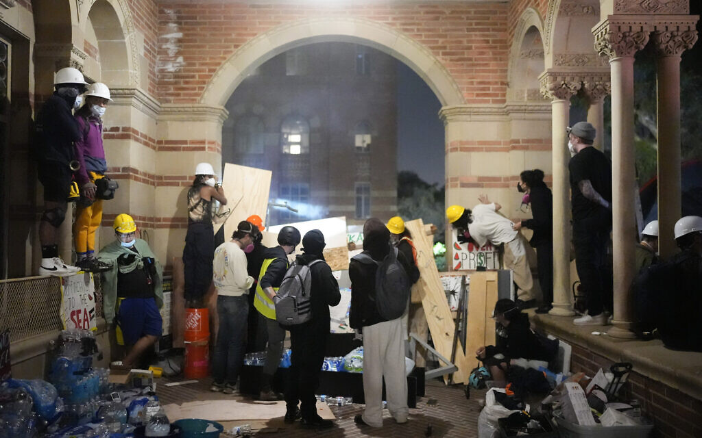  Des manifestants pro-palestiniens et anti-Israël observant les activités de la police derrière une barricade de fortune sur le campus de l'UCLA, à Los Angeles, le 1er mai 2024. (Credit : Jae C. Hong/AP)