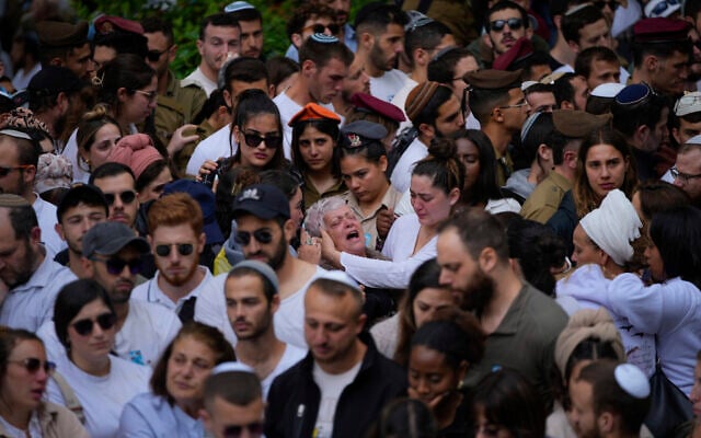 Des membres des familles des soldats tombés au combat ou des amis sur leurs tombes lors de Yom HaZikaron au cimetière du mont Herzl à Jérusalem, le 13 mai 2024. (Crédit : AP Photo/Ohad Zwigenberg)