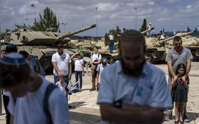 Des Israéliens observent deux minutes de silence pendant Yom HaZikaron sur le site commémoratif du corps blindé à Latrun, le 13 mai 2024. (Crédit : AP Photo/Ariel Schalit)