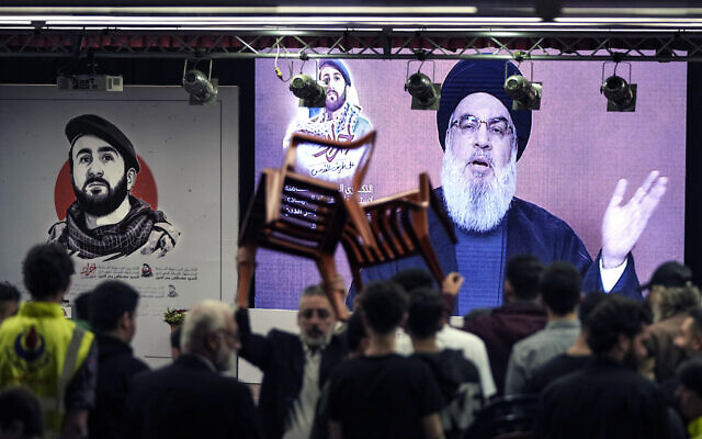 Des partisans du Hezbollah, soutenu par l'Iran, écoutant le discours du chef du Hezbollah, Sayyed Hassan Nasrallah, qui s'exprime par liaison vidéo, dans la banlieue sud de Beyrouth, au Liban, le 13 mai 2024. (Crédit : Hassan Ammar/AP)
