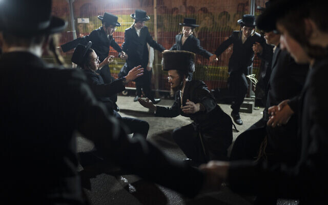 Des Juifs ultra-orthodoxes dansent autour d'un feu de joie lors de la fête de Lag BaOmer dans le quartier de Mea Sharim à Jérusalem, le 26 mai 2024. (Crédit : AP Photo/Leo Correa)