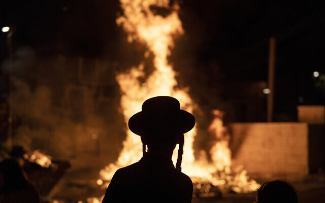 Un ultra-orthodoxe à côté d'un feu de joie pendant la fête de Lag BaOmer dans le quartier Mea Shearim de Jérusalem, le 25  mai 2024. (Crédit :  AP Photo/Leo Correa)