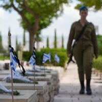 Des soldats déposant des fleurs et des drapeaux sur les tombes des troupes tombées au combat dans le cimetière militaire de Kiryat Shmona, à la veille de Yom HaZikaron, le 12 mai 2024. (Crédit : Ayal Margolin/Flash90)