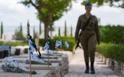 Des soldats déposant des fleurs et des drapeaux sur les tombes des troupes tombées au combat dans le cimetière militaire de Kiryat Shmona, à la veille de Yom HaZikaron, le 12 mai 2024. (Crédit : Ayal Margolin/Flash90)