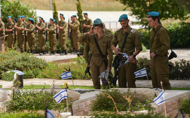 Des soldats déposent des fleurs et des drapeaux sur les tombes des soldats israéliens tombés au combat dans le cimetière militaire de Kiryat Shmona, le 12 mai 2024. (Crédit : Ayal Margolin/Flash90)