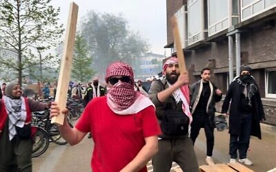 Des activistes anti-Israël brandissant des planches de bois avant de les utiliser pour frapper des étudiants à l'université d'Amsterdam, aux Pays-Bas, le 6 mai 2024. (Crédit : Autorisation)