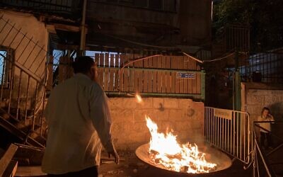 Un habitant juif de Sheikh Jarrah, à Jérusalem-Est, allume un feu de joie lors de la nuit de Lag BaOmer, le 25 mai 2024. (Charlie Summers/Times of Israel)
