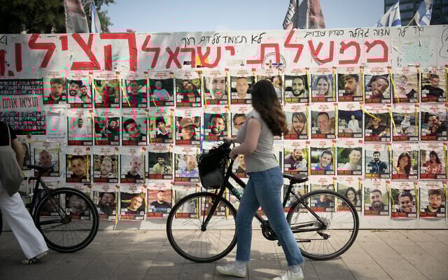 Des personnes passant devant des photos de personnes toujours retenues en otage par les terroristes du Hamas à Gaza, sur la Place des Otages, à Tel Aviv, le 1er mai 2024. (Crédit : Miriam Alster/Flash90) Des personnes passant devant des photos de personnes toujours retenues en otage par les terroristes du Hamas à Gaza, sur la Place des Otages, à Tel Aviv, le 1er mai 2024. (Crédit : Miriam Alster/Flash90)