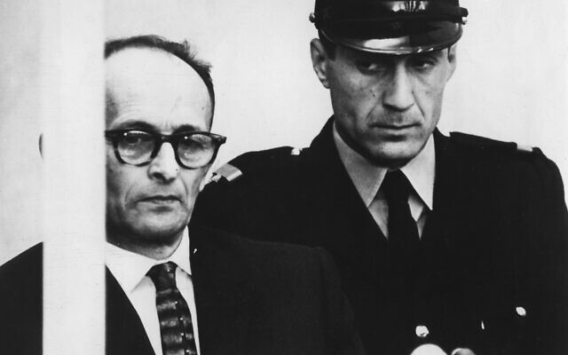 Adolf Eichmann, debout dans son box vitré à l'épreuve des balles, lors de la lecture des charges retenues contre lui au cours d'une procédure judiciaire dans le bâtiment Beit HaAm, à Jérusalem, le 12 avril 1961. (Crédit : Stringer/AP)