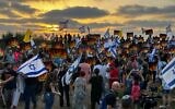 Des manifestants devant la résidence privée du Premier ministre Benjamin Netanyahu à Césarée tiennent des drapeaux israéliens et des pancartes avec les noms des communautés sur la frontière nord avec le Liban touchées par des incendies dus aux attaques de roquettes et de drones du Hezbollah, le 20 juin 2024. (Crédit : Amos Gil/Mouvement pro-démocratie)