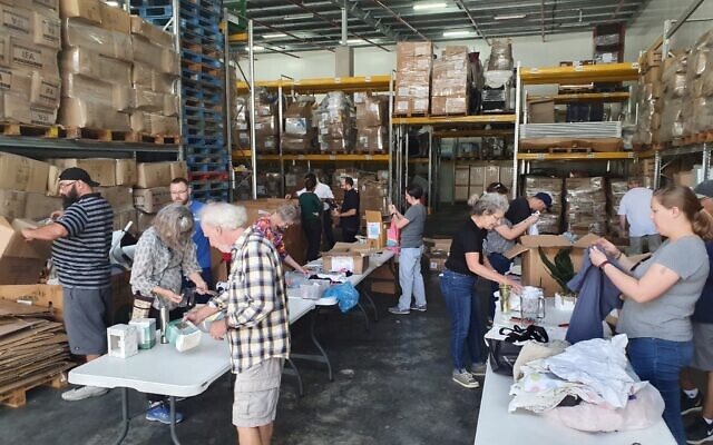 Les bénévoles et les coordinateurs de l'entrepôt de Social Delivery aidant à déballer et à trier les biens commerciaux excédentaires collectés auprès d'entreprises et d'organisations,à Beit Shemesh. (Crédit : Autorisation)