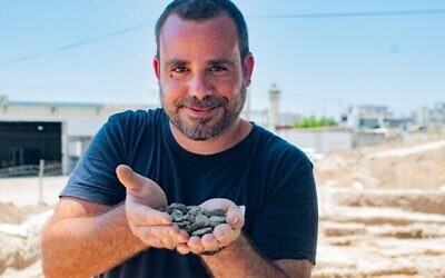 L'archéologue Shahar Krispin tient une partie des pièces de Lod après leur découverte, sur une image publiée le 16 juin 2024. (Crédit : Yoli Schwartz/IAA)