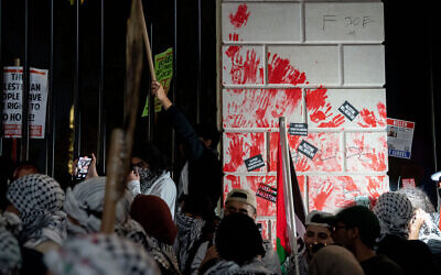 Des manifestants pro-palestiniens vandalisant la clôture devant la Maison Blanche avec des empreintes de mains rouges lors d'une manifestation contre Israël, à Washington, le 4 novembre 2023. (Crédit : Stefani Reynolds/AFP)