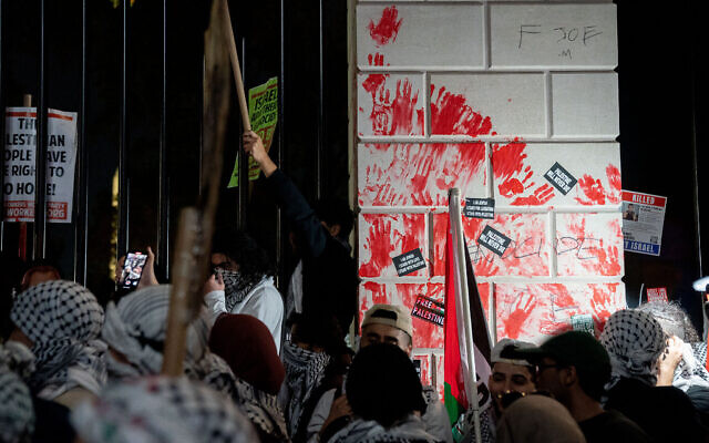 Des manifestants pro-palestiniens vandalisant la clôture devant la Maison Blanche avec des empreintes de mains rouges lors d'une manifestation contre Israël, à Washington, le 4 novembre 2023. (Crédit : Stefani Reynolds/AFP)