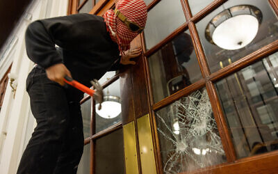 Un activiste anti-israélien casse une fenêtre du bâtiment Hamilton Hall, à l'université de Columbia, pour installer une chaîne empêchant l'entrée des autorités dans l'immeuble à New York City, le 30 avril 2024. (Crédit : Alex Kent/Getty Images/AFP)