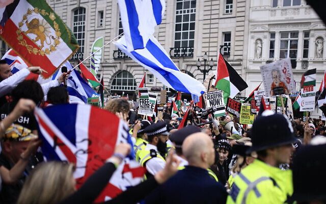Un groupe de manifestants pro-israéliens brandissent des couleurs israéliens lors d'un défilé pro-palestinien dans le centre de Londres, le 18 mai 2024. (Crédit : BENJAMIN CREMEL / AFP) Un groupe de manifestants pro-israéliens brandissent des couleurs israéliens lors d'un défilé pro-palestinien dans le centre de Londres, le 18 mai 2024. (Crédit : BENJAMIN CREMEL / AFP)