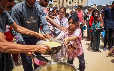 Des Palestiniens déplacés faisant la queue pour recevoir de la nourriture, à Rafah, dans le sud de la bande de Gaza, le 19 mai 2024 (Crédit : AFP)