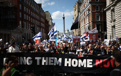 Des manifestants brandissant des pancartes et des drapeaux israéliens participent à une marche dans le centre de Londres, le 2 juin 2024, pour attirer l'attention sur le sort des otages toujours détenus à Gaza. (Crédit : HENRY NICHOLLS / AFP)