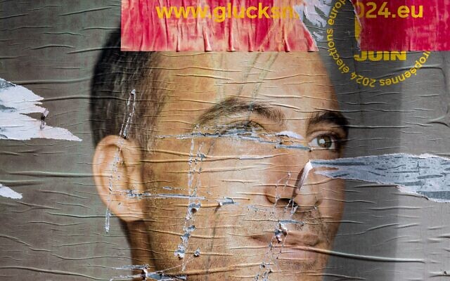 Une affiche de campagne de Raphaël Glucksmann, candidat principal du Parti socialiste français pour les élections européennes 2024, déchirée et comportant une croix gammée, à Paris, le 3 juin 2024. (Crédit : JOEL SAGET / AFP)