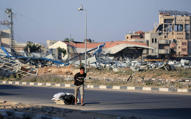 Un jeune Palestinien tire un sac de tuyaux collectés sur la route à Al-Maghazi au milieu des combats dans le centre de la bande de Gaza le 5 juin 2024 (Crédit : Eyad BABA / AFP).