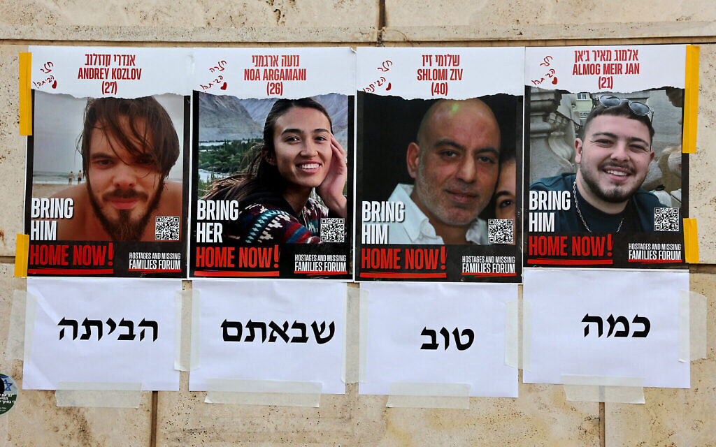 Des affiches représentant les portraits des otages israéliens sauvés, Andrey Kozlov, 27 ans, Noa Argamani, 26 ans, Shlomi Ziv, 41 ans, et Almog Meir Jan, 22 ans, placardées sur un mur de Tel Aviv le 8 juin 2024. En dessous, on peut lire "c'est si bon que vous soyez rentrés à la maison". (Crédit : Gil Cohen-Magen/AFP)