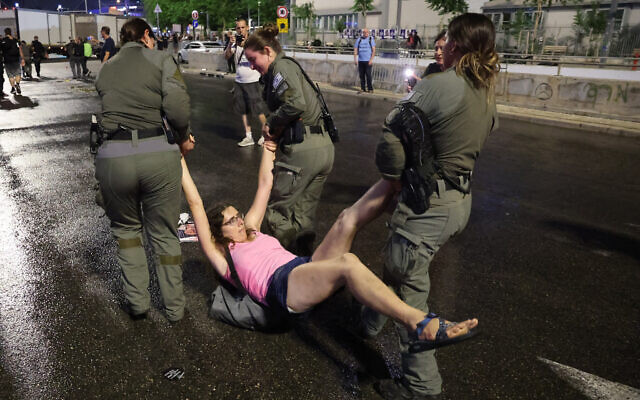 La police arrêtant une manifestante lors d'un rassemblement réclamant la libération des otages détenus à Gaza depuis le 8 octobre, à Tel Aviv, le 8 juin 2024. (Crédit : Jack Guez/AFP)