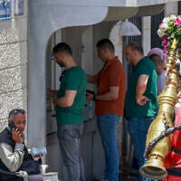 Des Palestiniens faisant la queue pour retirer de l'argent à un distributeur automatique sur le marché principal de la ville de Ramallah, en Cisjordanie, le 9 juin 2024. (Crédit : Jaafar Ashtiyeh/AFP)