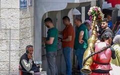 Des Palestiniens faisant la queue pour retirer de l'argent à un distributeur automatique sur le marché principal de la ville de Ramallah, en Cisjordanie, le 9 juin 2024. (Crédit : Jaafar Ashtiyeh/AFP)