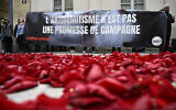 Des membres du collectif "Nous Vivrons", un groupe de lutte contre l'antisémitisme, lançant des pétales de roses pour symboliser la "fin" du parti socialiste français, alors qu'ils protestent avec une banderole "L'antisémitisme n'est pas une promesse de campagne" lors d'une manifestation devant le bâtiment de la Maison de la Chimie où le "Nouveau Front Populaire", un pacte électoral entre plusieurs partis de gauche, devrait être annoncé plus tard dans la journée, à Paris, le 14 juin 2024. (Crédit : Julien De Rosa/AFP)
