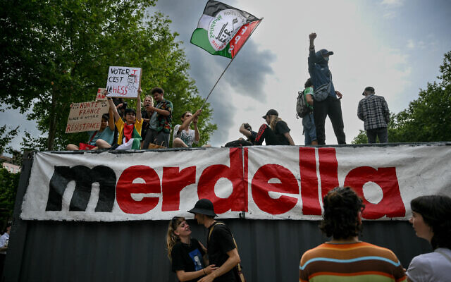 Des manifestants brandissant un drapeau palestinien et affichant un slogan mélangeant le mot "merde" et le nom de famille du président du parti d'extrême droite français Rassemblement national (RN), Jordan Bardella, lors d'un rassemblement contre l'extrême droite, à Lyon, le 16 juin 2024. (Crédit : Olivier Chassignole/AFP) Des manifestants brandissant un drapeau palestinien et affichant un slogan mélangeant le mot "merde" et le nom de famille du président du parti d'extrême droite français Rassemblement national (RN), Jordan Bardella, lors d'un rassemblement contre l'extrême droite, à Lyon, le 16 juin 2024. (Crédit : Olivier Chassignole/AFP)