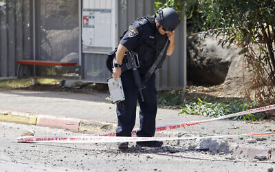 Un officier de police israélien inspecte un site où des roquettes lancées depuis le sud du Liban ont frappé à Kiryat Shmona dans le nord d'Israël, le 19 juin 2024. (Crédit : Jalaa MAREY / AFP)