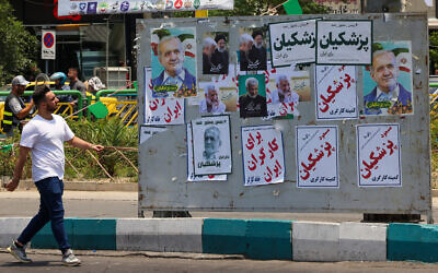 Photo d'illustration : Un homme passe devant des affiches électorales à Téhéran en amont des élections qui remplaceront, le 28 juin, le président Ebrahim Raisi, tué dans un accident d'hélicoptère, le 20 juin 2024. (Crédit : Atta Kenare / AFP)