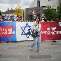 Des manifestants tenant une banderole "violée à 12 ans parce que juive" lors d'une manifestation à l'appel d'associations dont SOS Racisme et la Fondation des femmes pour dénoncer l'antisémitisme, à Paris le 20 juin 2024, après le viol collectif antisémite d'une jeune fille de 12 ans à Courbevoie, dans la banlieue parisienne. (Crédit : Zakaria Abdelkafi/AFP)