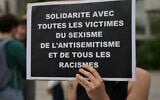 Une manifestante brandit une pancarte indiquant « solidarité avec toutes les victimes du sexisme, de l'antisémitisme et de toutes les formes de racisme » lors d'une manifestation convoquée par des associations dont SOS Racisme et la Fondation des Femmes pour dénoncer l'antisémitisme, à Paris le 20 juin 2024, après le viol collectif antisémite d'une jeune fille de 12 ans à Courbevoie, en banlieue parisienne. (Crédit : Zakaria Abdel kafi/AFP)