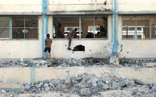 Des Palestiniens, au milieu des décombres d'un bâtiment scolaire de l'ONU, à Khan Younès, le 21 juin 2024. (Crédit : Eyad Baba/AFP)