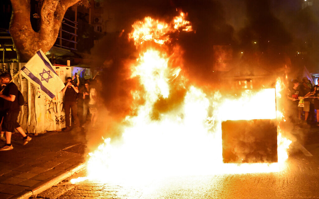 Des proches et des soutiens des Israéliens retenus en otage à Gaza par le Hamas depuis le 7 octobre allument un feu lors d'une manifestation appelant à leur libération à Tel Aviv, le 22 juin 2024. (Crédit : JACK GUEZ / AFP)