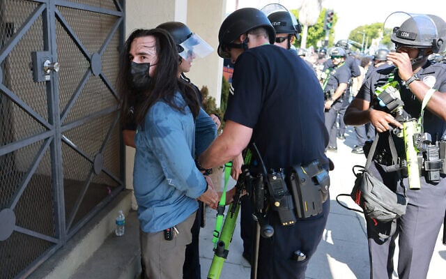 Un homme est arrêté par des officiers de la police de Los Angeles (LAPD) alors que des partisans d'Israël se heurtent à des manifestants anti-Israël qui bloquaient l'accès à la synagogue orthodoxe Adas Torah, à Los Angeles, le 23 juin 2024. (Crédit : David Swanson/AFP)