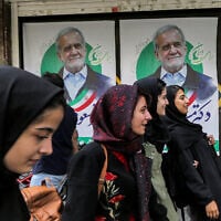 À  l'approche du scrutin, des femmes passant devant les affiches électorales du candidat réformateur à la présidence iranienne, Massoud Pezeshkian, dans une rue de Téhéran, le 26 juin 2024. (Crédit : Raheb Homavandi/AFP)