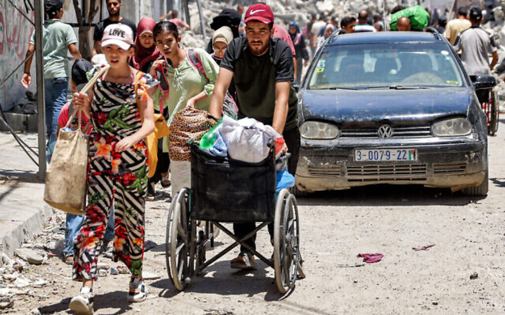 Un homme pousse un fauteuil roulant chargé d'objets lors de l'évacuation avec d'autres personnes du quartier de Tuffah dans l'est de la ville de Gaza, le 27 juin 2024. (Crédit : Omar Al-Qattaa/AFP).