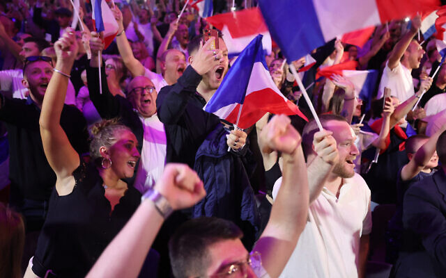 Des partisans réagissant alors que l'ancienne présidente du groupe parlementaire d'extrême droite du Rassemblement national (RN), Marine Le Pen, prononce un discours lors de la soirée de résultats du premier tour des élections législatives à Henin-Beaumont, dans le nord de la France, le 30 juin 2024. (Crédit : François Lo Presti/AFP)