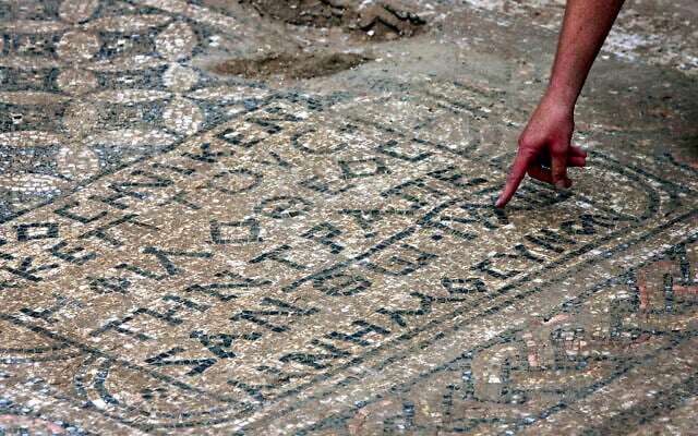 Un archéologue israélien montrant un sol décoré vieux de près de 1 800 ans provenant d'une salle de prière paléochrétienne que des archéologues israéliens ont découvert à proximité de la prison de Megiddo, le 6 novembre 2005. (Crédit : Ariel Schalit/AP)