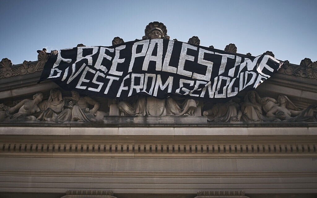 Un manifestant anti-Israël (en haut à gauche) accrochant un drapeau au sommet du Brooklyn Museum alors qu'il occupe le bâtiment pour protester contre la guerre d'Israël contre le Hamas à Gaza, à New York, le 31 mai 2024. (Crédit : Andres Kudacki/AP) Un manifestant anti-Israël (en haut à gauche) accrochant un drapeau au sommet du Brooklyn Museum alors qu'il occupe le bâtiment pour protester contre la guerre d'Israël contre le Hamas à Gaza, à New York, le 31 mai 2024. (Crédit : Andres Kudacki/AP)